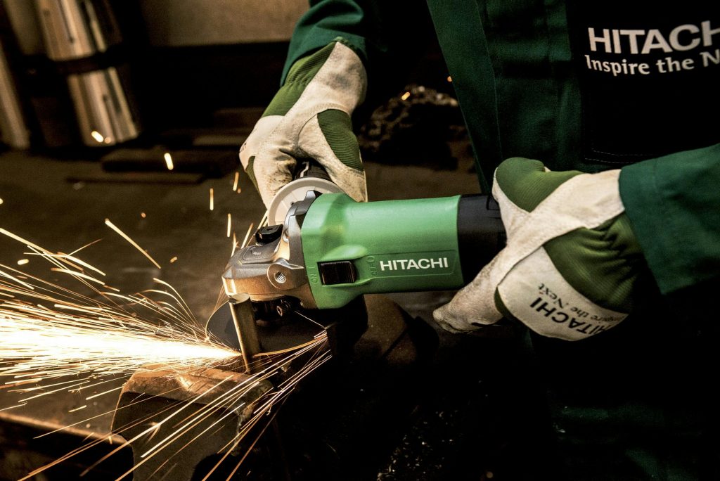 Close-up of a worker using an angle grinder in a workshop, producing bright sparks.